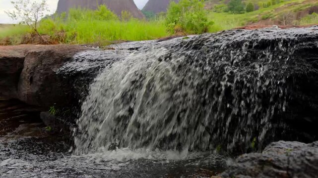 A peaceful natural scene of a small waterfall formed by a rural stream flowing over rocks in Aguia Branca, Espirito Santo, Brazil