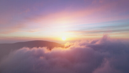 Obraz premium Aerial view of a serene sunrise above the clouds with a mountain range in the distance under a vibrant purple and orange sky.
