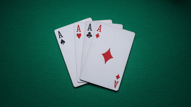 A set of four ace playing cards fanned out on a green felt table