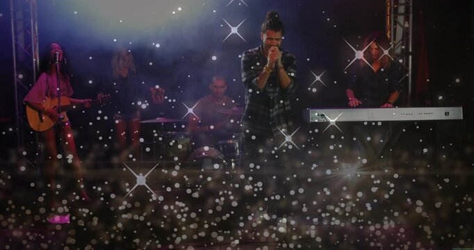 Lead singer starting song, band playing for fans while sparkle drifting across leaving faces clear