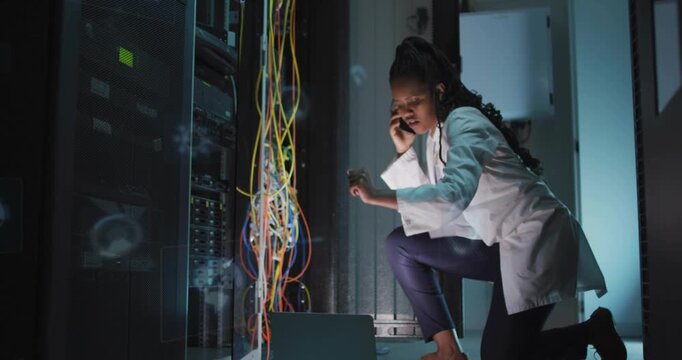 IT tech kneeling accessing open server rack, tracing colorful cables while testing network on phone