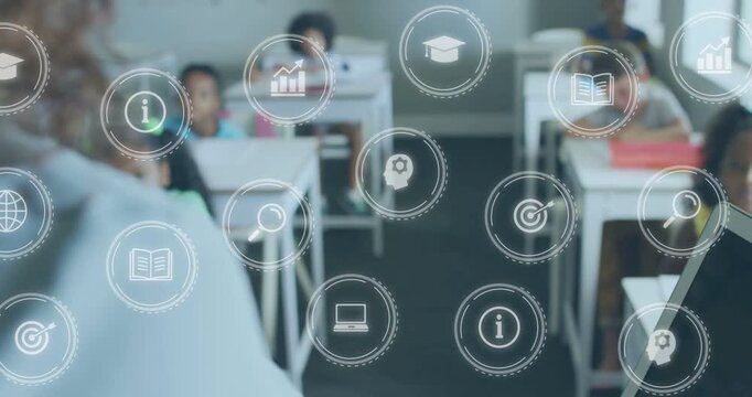 Teacher gesturing, teaching and initiating transparent school icons drifting across desks, laptop