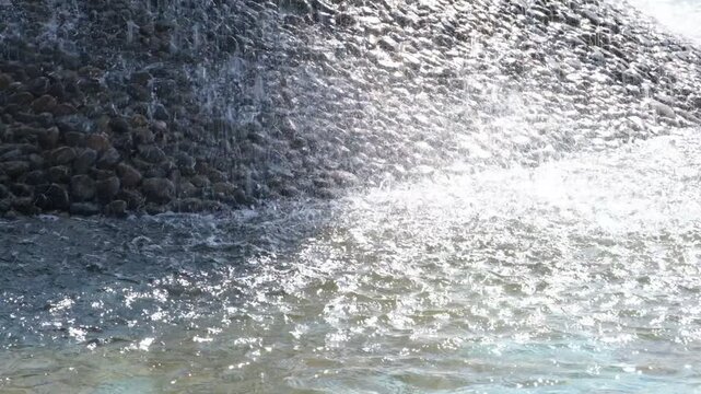 Waterfall fountain flows in streams. Waters running down. Water in the fountain shimmers and shines. 