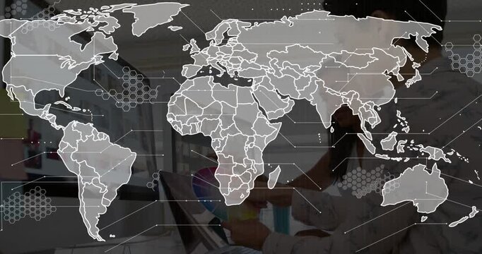 2 women designers using color wheel, tablet while world map overlay appearing mapping global hexes