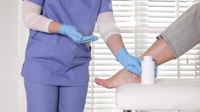 Podologist in medical gloves applying talcum powder onto patient's foot in clinic, closeup