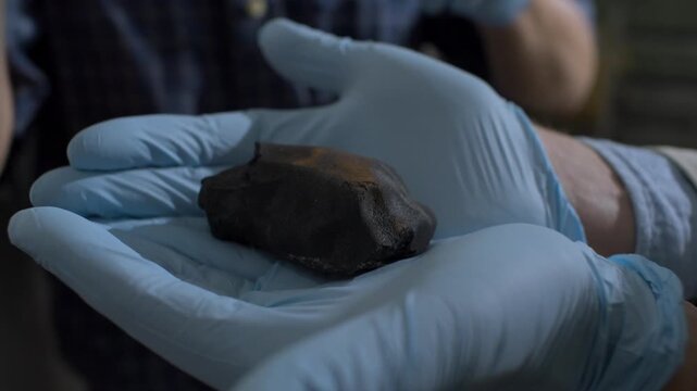 Scientist wearing protective gloves holding a rare meteorite for analysis and research