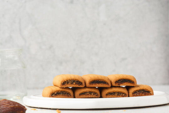 closeup view of date cookies on a white marble countertop, date filled sugar cookies on white textured background, homemade maamoul cookie bars on white tray