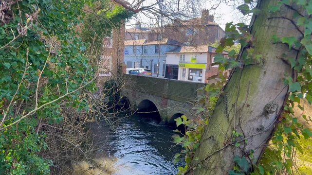 The River Colne flows under a bridge beneath Church Street in Staines-upon-Thames, England, UK