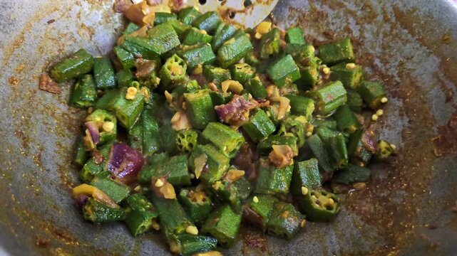 Spicy bhindi masala being cooked in pan. Indian okra fry