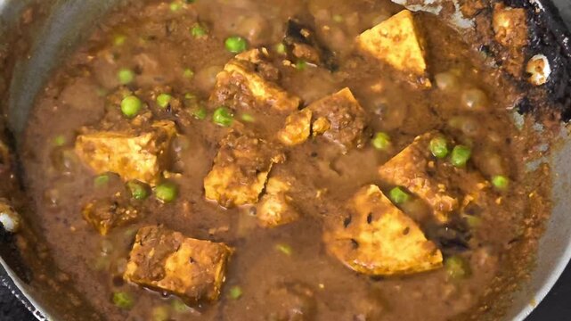 Close up of delicious indian matar paneer curry boiling and simmering in a cooking pan