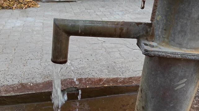 Fresh water flowing from a traditional rusty iron hand pump