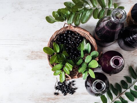 Fresh bayberries plum wine bamboo basket green leaves purple juice bottles scattered fruits white wooden table overhead oriental summer scene