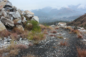 A scenic view from a high mountain ridge in Buner, Pakistan, looking down over a misty valley and...