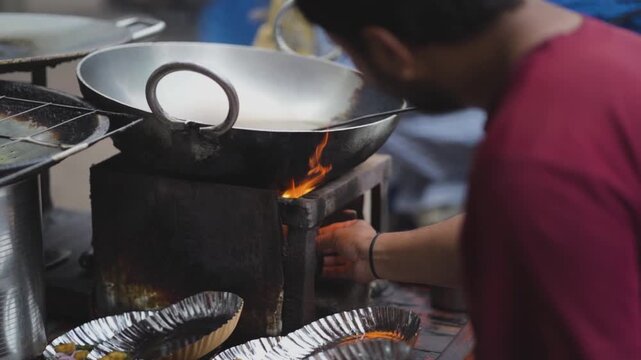 Street vendor heating oil in kadhai, Indian street food frying setup close up, Preparing oil in wok for street cooking, Roadside cook lighting stove for frying stock video.