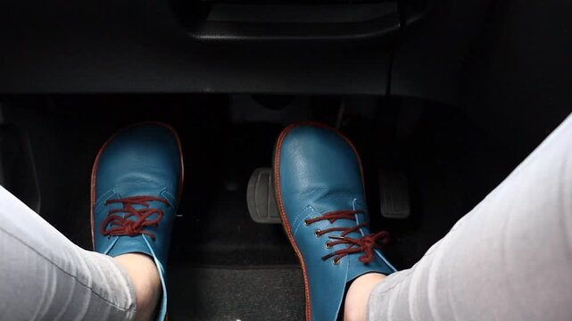 First-person perspective of a driver controlling accelerator and brake pedals inside a car. Concept of driving, vehicle control. Clean interior shot with focus on foot movement and driving action.