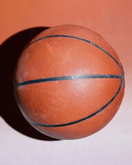 Obraz premium Classic Orange Basketball with Textured Surface Resting on a Two Tone Brown and Beige Background for Professional Sports Equipment Advertising and Marketing