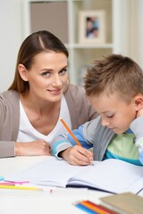 Fototapeta premium Mother helping her young child with homework at a bright kitchen table together