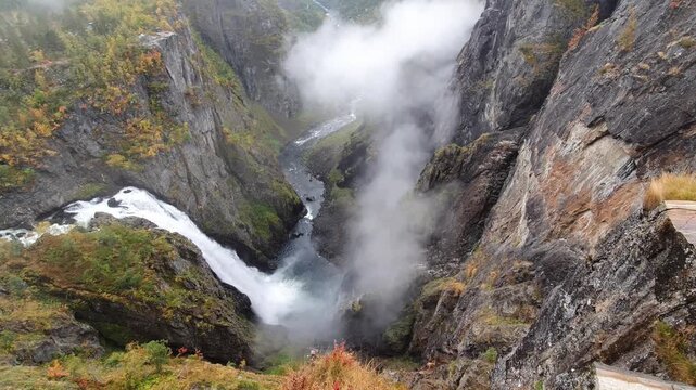 Majestic Voringsfossen waterfall cascading into a misty gorge during autumn in Norway