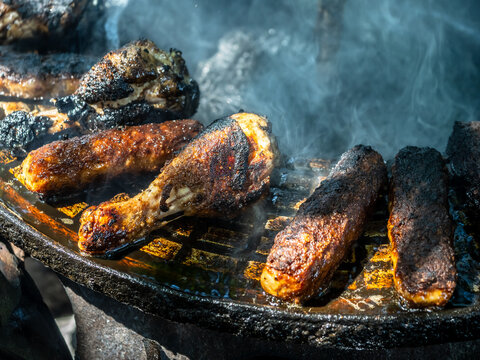 Barbecue grilling pork sausages, mici, mititei and chicken legs over open fire