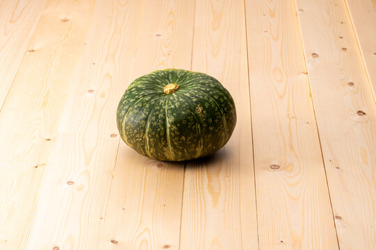 木製テーブルの上に緑色かぼちゃが置いてある。