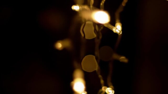 A mesmerizing close-up video of shimmering golden light with delicate string lights and abstract refractions, a slow cinematic dolly video revealing an opulent golden bokeh background. Luxury