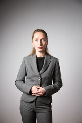 Vertical photo. A woman in a business suit with her arms folded.