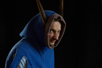 Portrait of an angry man in a medieval hood with pheasant feathers on a black background