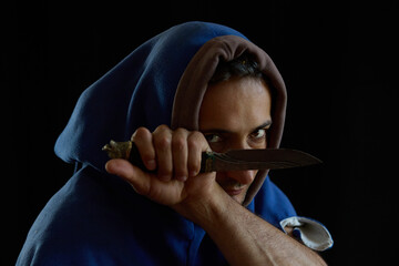 Naklejka premium A portrait of a man in a medieval hood holding a knife