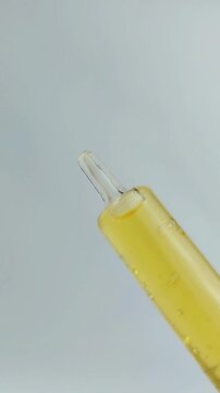 Process of opening the cap of a golden yellow beauty serum. Close up view, skincare routine, precise hand movement, cosmetic product detail on clean background.