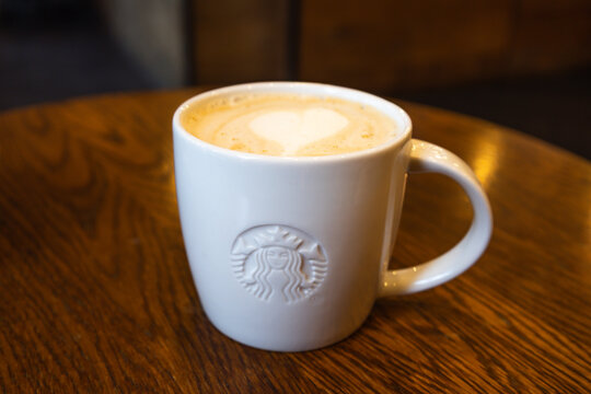 White Starbucks mug with heart latte art on a wooden cafe table. London, UK, 8 July 2023