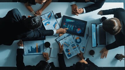 Fototapeta premium Top down aerial view of smart project manager present growth graph while marketing team analyze chart at meeting table with.laptop, tablet and stock market financial statistic document. Directorate.