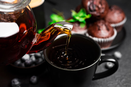 Tea with muffins on a dark background. Chocolate muffins with blueberries. Black tea with mint. High quality photo
