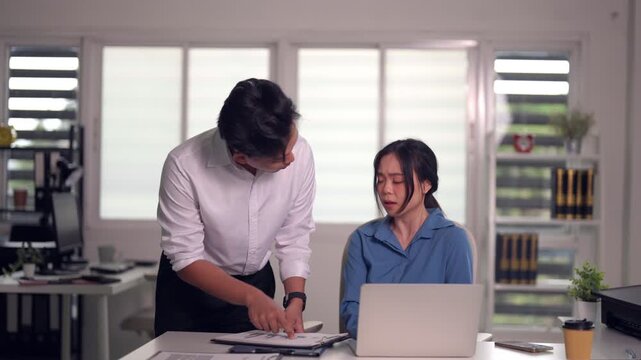 Asian businesswoman explains project issues to male colleague discussing solutions in modern office environment collaborative team problem solving focus