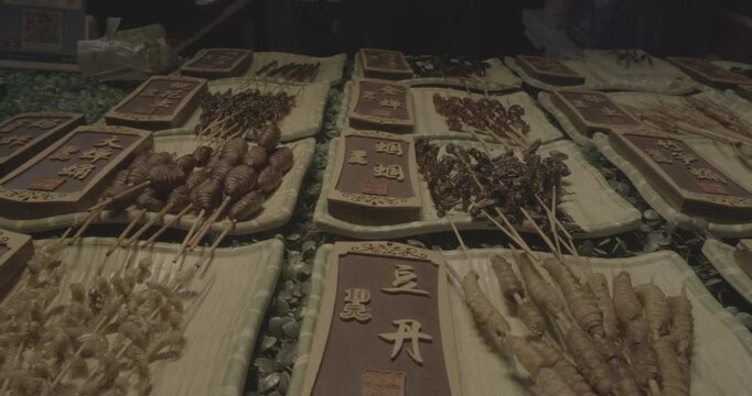 Chengdu, Sichuan, China. Ungraded C LOG 2, Insects on sticks at local Chinese market, close-up view. Various cooked insects thread on skewers. New Source Of Protein, Lipids, Minerals And Vitamins