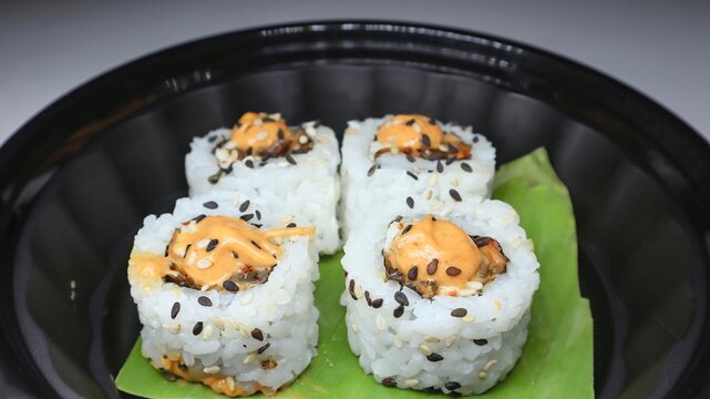 Closeup of shot of mouth-watering sushi roll filled with variety of ingredients including avocado, cucumber served in a restaurant