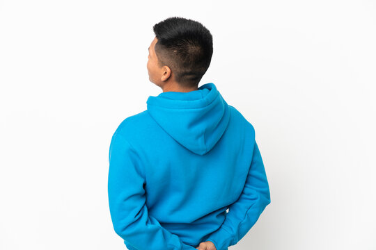 Young Ecuadorian man isolated on white background in back position and looking back