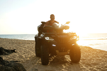 A man engages in extreme ATV riding on sand beach early in the morning © romaset
