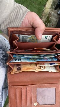 Offene Geldb&ouml;rse mit Bargeld in der Hand, Einnahmen auf dem Tr&ouml;delmarkt, Fokus auf Bargeldzahlung und Verkauf im Alltag, authentische Aufnahme mit Copyspace