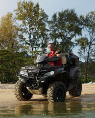 Fototapeta premium A man engages in extreme ATV riding on sand beach early in the morning