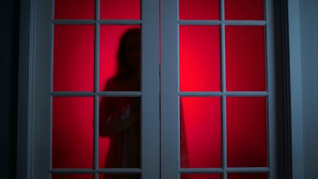 A shadowy, mysterious figure stands eerily behind a frosted glass door, silhouetted intensely against a dramatic and unsettling red light, creating an ominous atmosphere of psychological suspense,