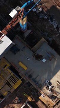 Drone shot of a multi-level concrete building frame with scaffolding, stairs, and organized construction materials on-site, highlighting structural development and engineering progress.