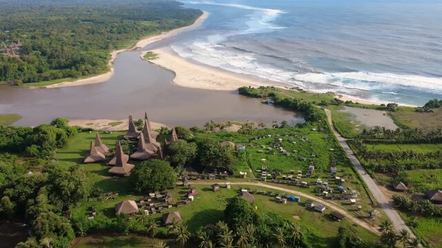 Aerial View of Ratenggaro Traditional Village with Tall Thatched Roof Houses by the River Mouth and Beach in Sumba, Indonesia