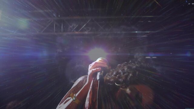 Female singer with mic singing 1st note, tossing hair on music stage while lights creating flares