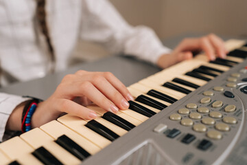 Obraz premium Close-up hands of unrecognizable young girl playing digital piano at home, learning music, practicing keyboard skills, enjoying musical education as hobby