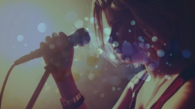 Female singer adjusting mic, performing while camera pulling back and bokeh floating over performer