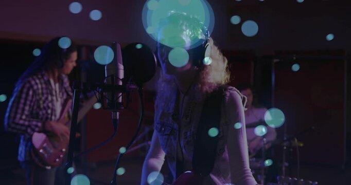 Lead singer starting studio take, singing, strumming while band keeping time under blue bokeh