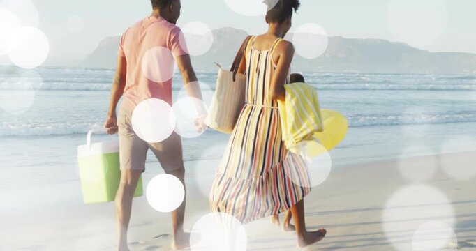 Family walking to surf for travel, parents with cooler and tote, kids running, bokeh over family