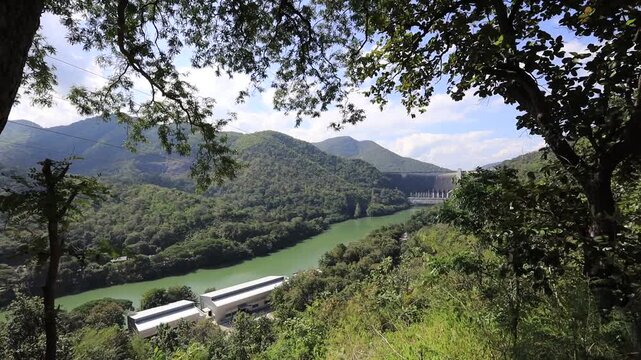 The video background features a natural aerial view of the Bhumibol Dam in Tak province, Thailand, which effectively stores water and sustains agricultural crops.