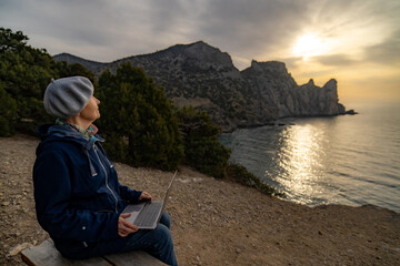 Woman working remotely laptop cliffs seaside view sunset