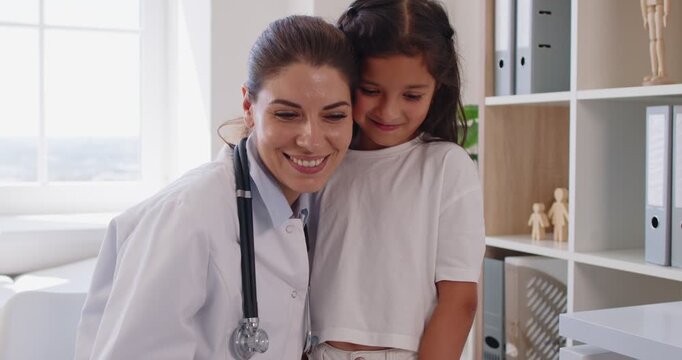 In medical clinic, a pediatrician gives a warm hug to a child patient, expressing compassion, care, and support that build trust after a gentle exam. Doctor and child share a reassuring hug.